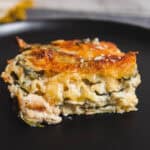 Savory spinach and cheese lasagna with crispy golden top on black plate, homemade Italian casserole, cheesy layered pasta dish, close-up of fresh baked lasagna, hearty comfort food recipe photo.
