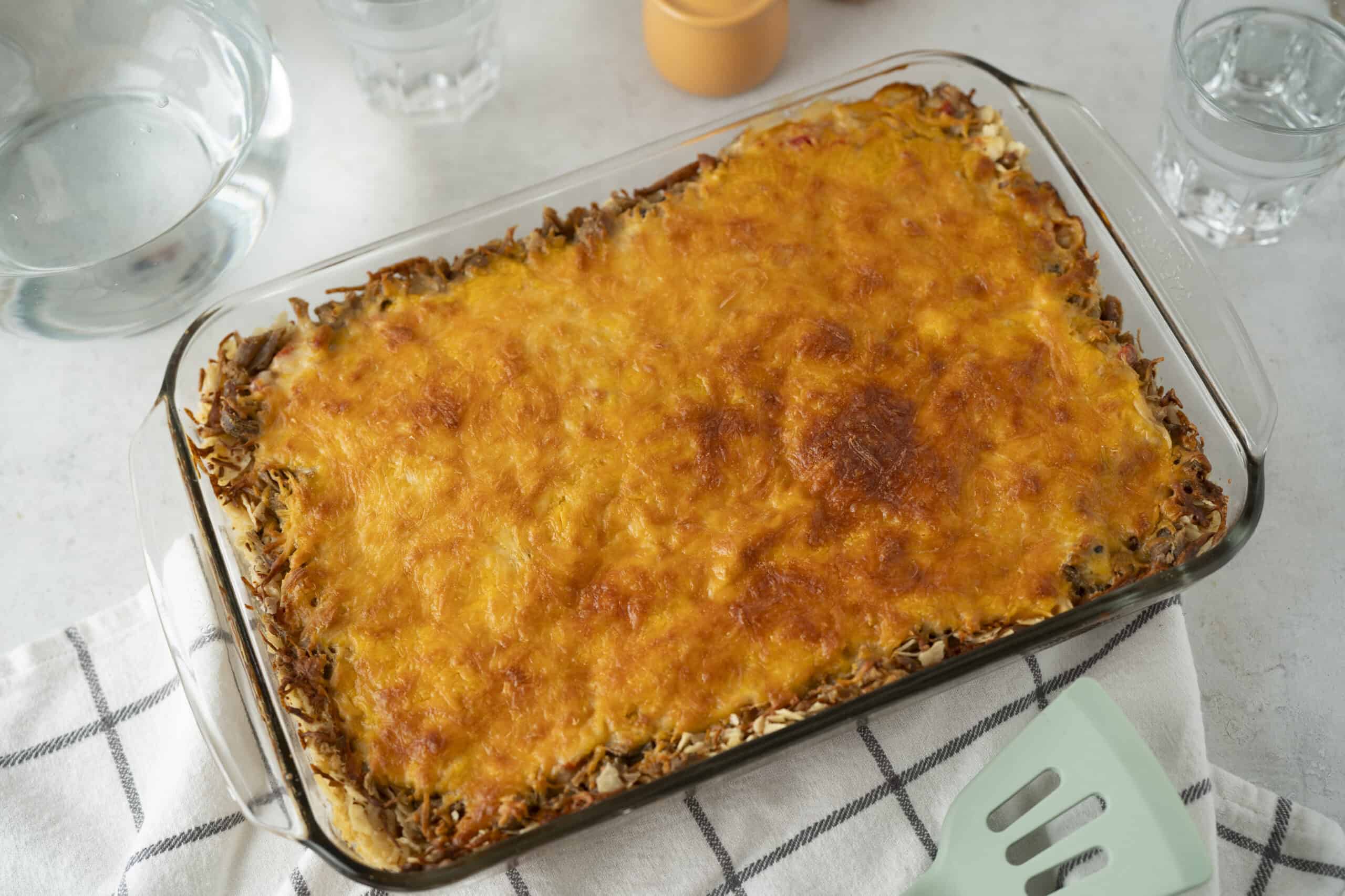 Creamy baked ground beef and pasta casserole with melted cheese on top, served in a glass baking dish for family dinner or meal prep.