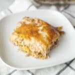 Creamy chicken and cheese casserole with a golden melted cheese topping, served on a white plate for a hearty, comforting meal.