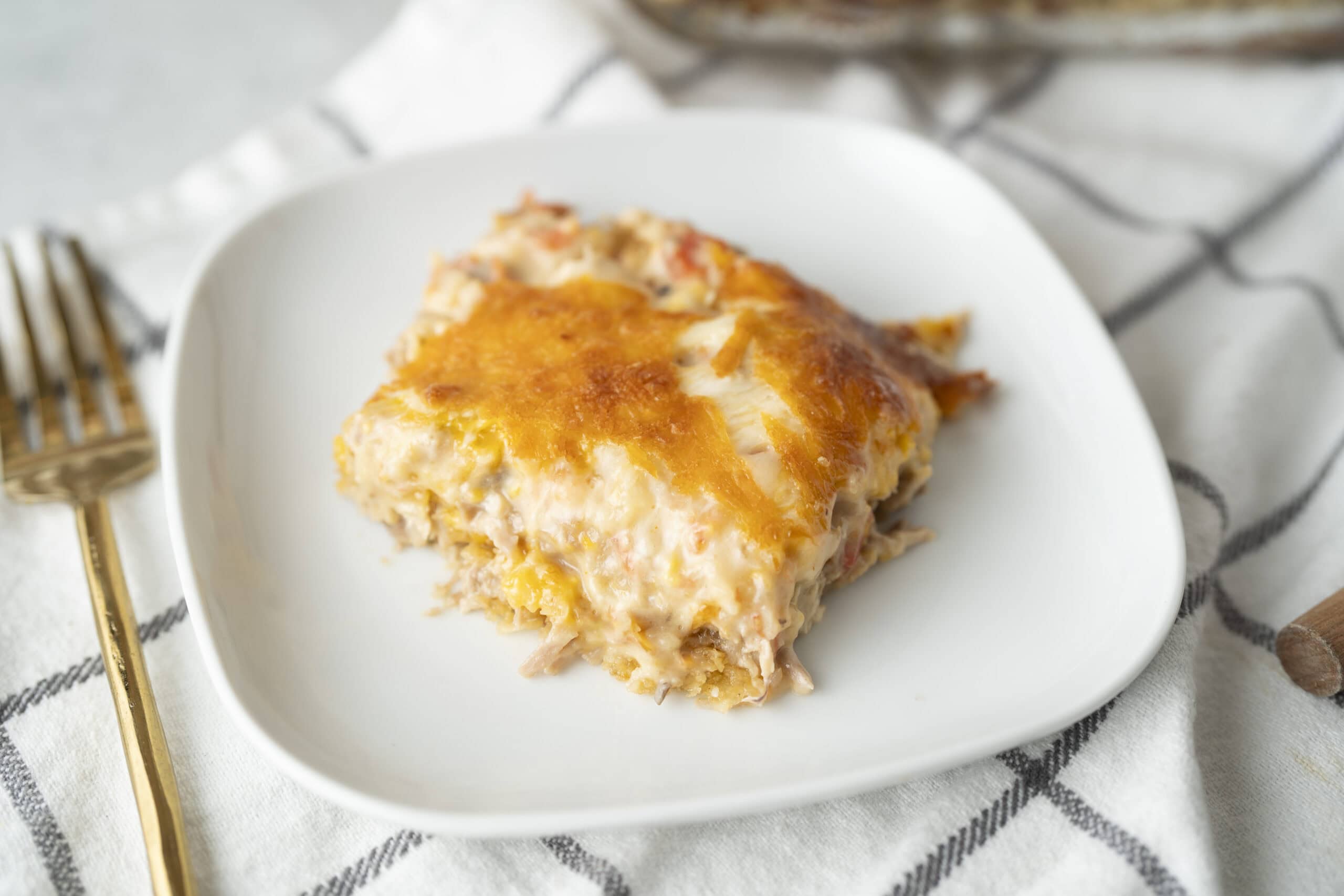 Creamy chicken and cheese casserole with a golden melted cheese topping, served on a white plate for a hearty, comforting meal.