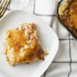 Creamy chicken and rice casserole topped with melted cheese, served on a white plate with a gold fork, featuring a baked dish with savory ingredients and a golden cheese crust, perfect for comfort food.