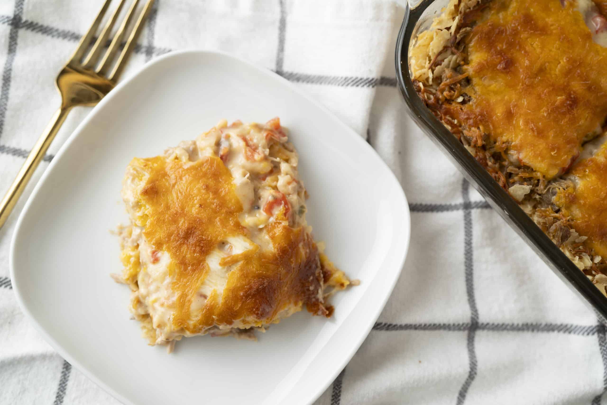 Creamy chicken and rice casserole topped with melted cheese, served on a white plate with a gold fork, featuring a baked dish with savory ingredients and a golden cheese crust, perfect for comfort food.
