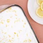 Freshly grated lemon zest on creamy dessert in a glass dish, with a plate of sliced lemons on the side, perfect for lemon-flavored recipes and dessert toppings.
