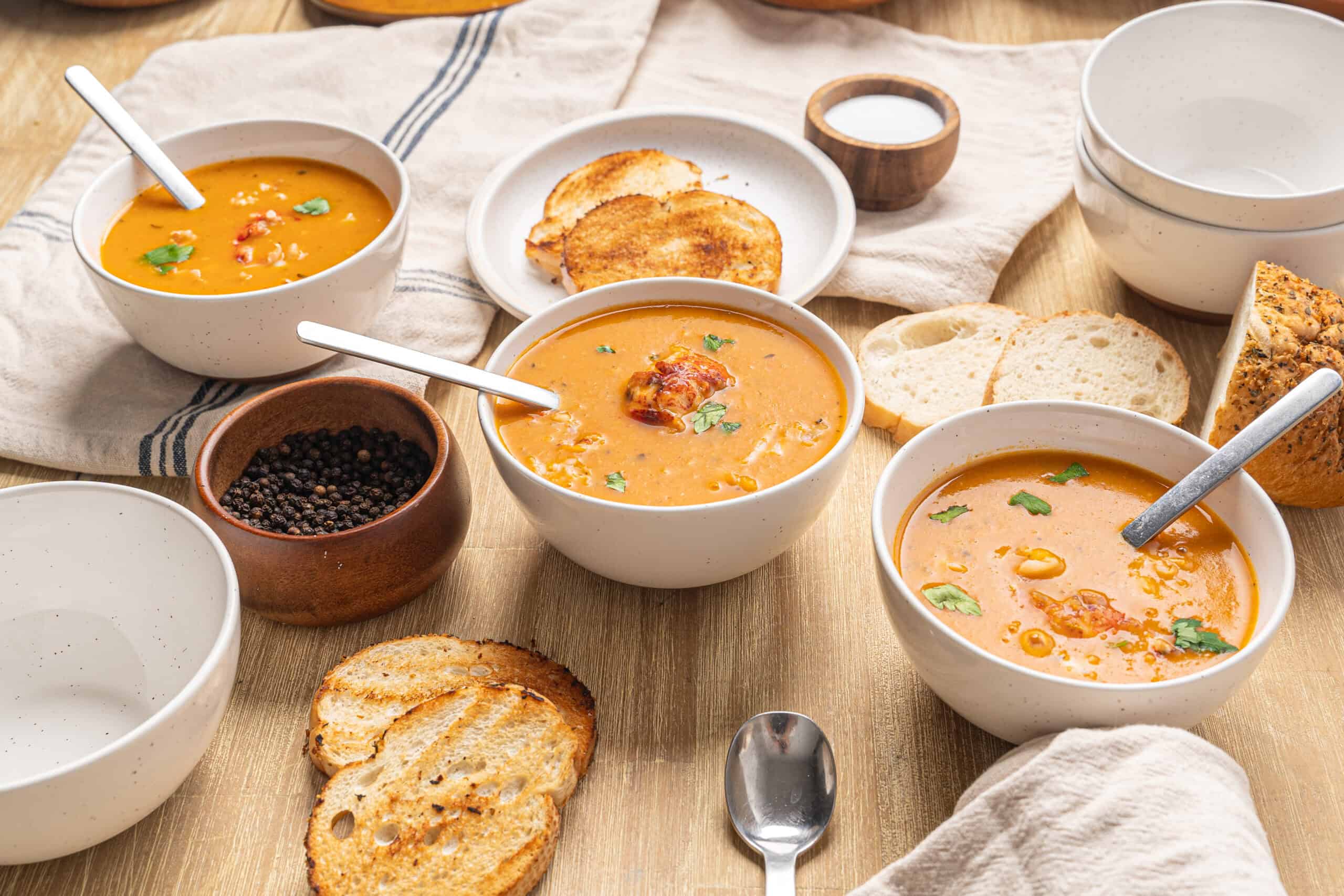 Creamy tomato soup with fresh herbs served in white bowls with toasted bread slices and spices, perfect for cozy, nutritious meals.