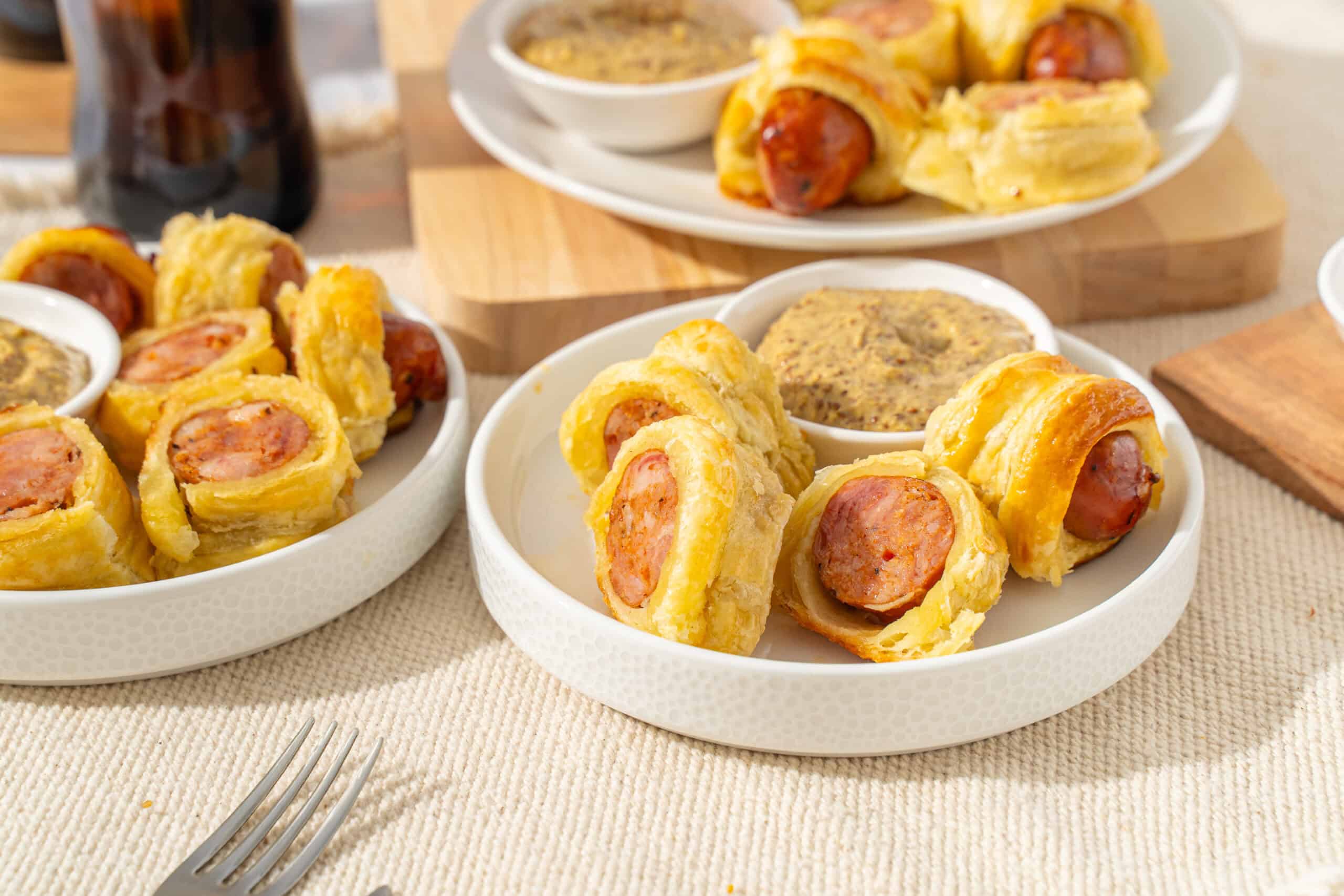 Golden fried sausage rolls served with mustard dipping sauce and mustard seeds on the side, perfect for quick snacks or parties.