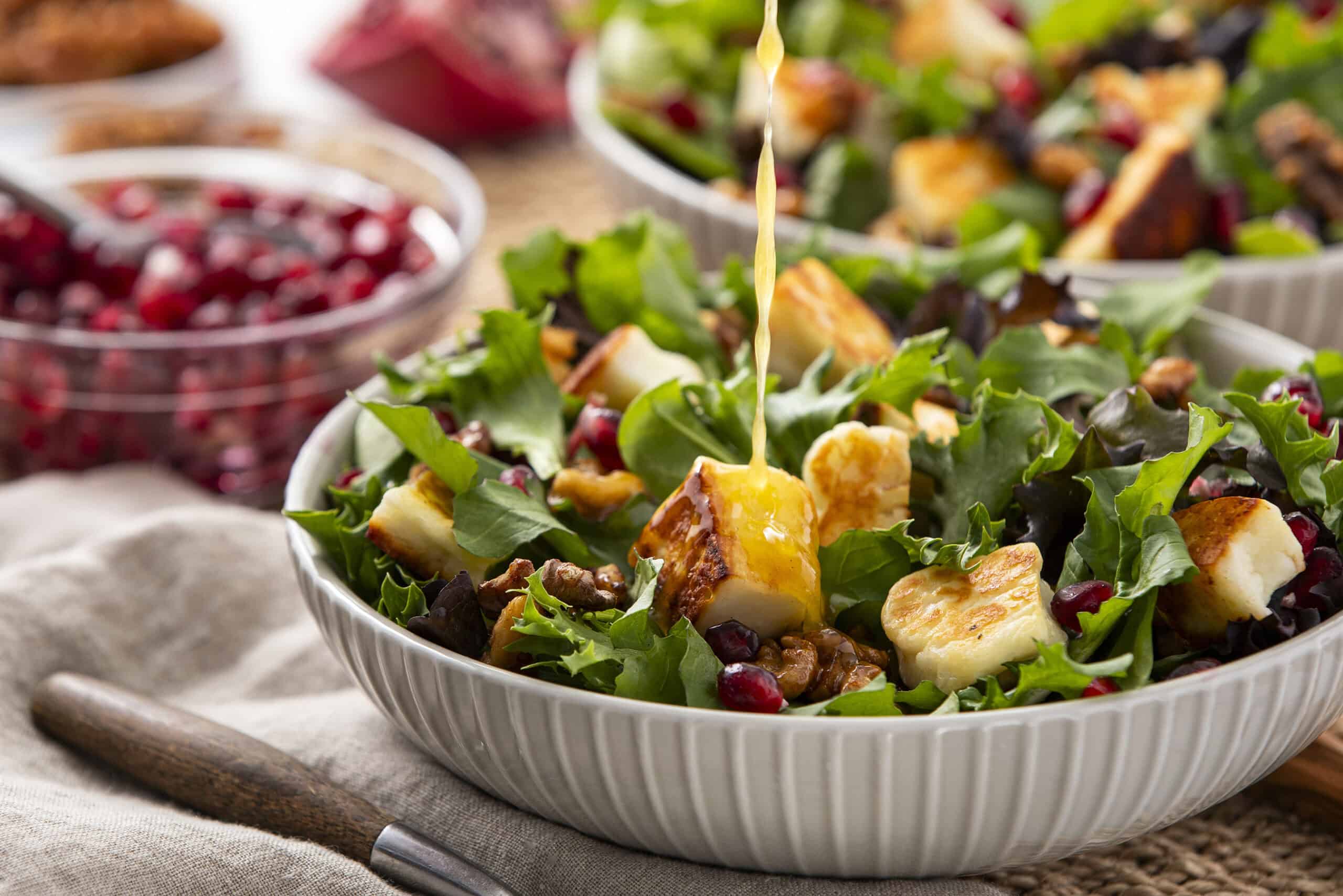 Fresh pomegranate and goat cheese salad with mixed greens, walnuts, and honey vinaigrette on a white bowl, perfect for healthy eating and nutritious meal ideas.