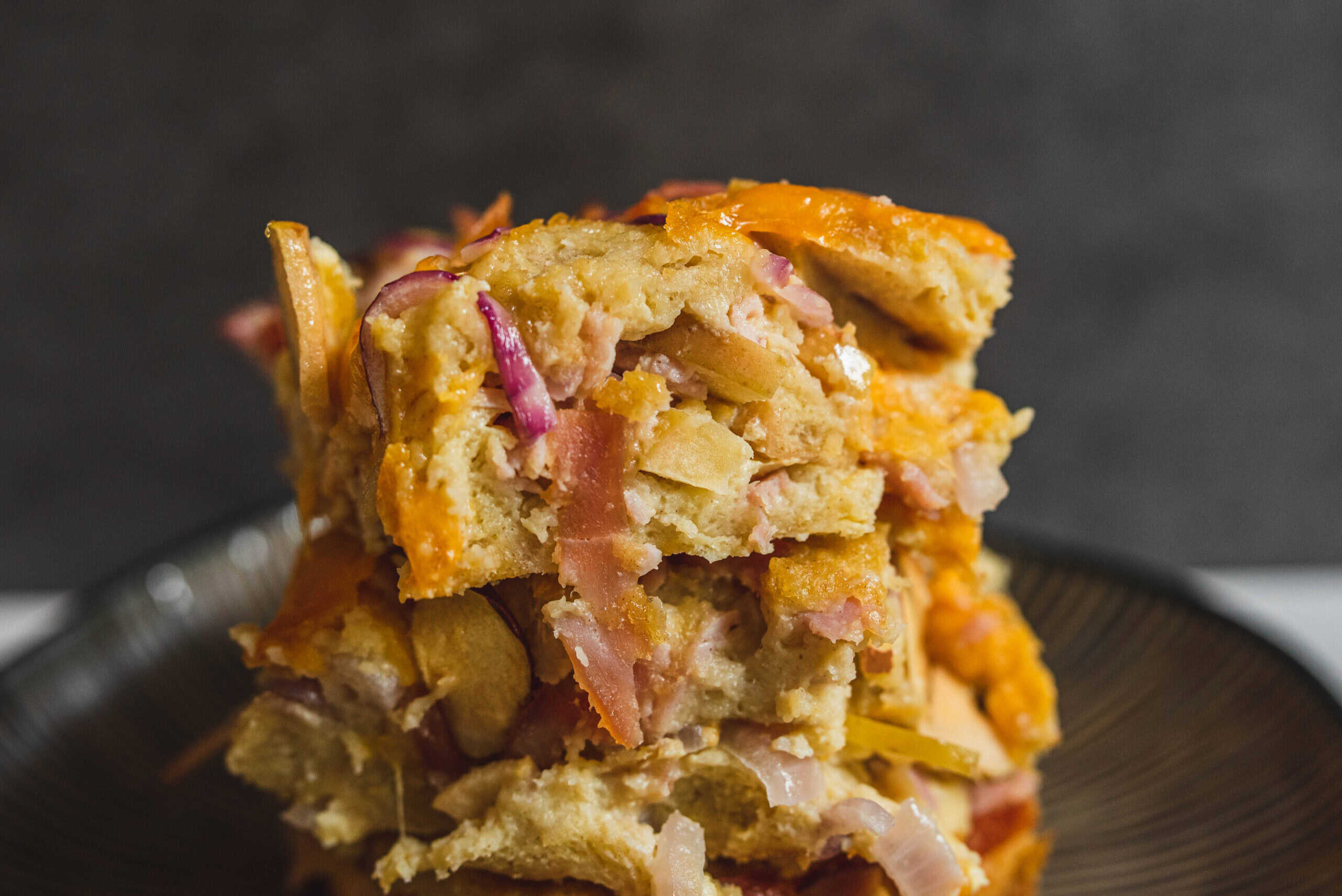 Crispy vegetable and ham casserole with cheese, baked to golden perfection, served on a dark plate. Delicious comfort food recipe perfect for family gatherings and dinner.