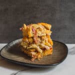 Buttermilk chicken casserole with vegetables and cheese on black plate, ready to serve, comforting baked dish, crispy top, home-cooked meal, hearty comfort food, modern kitchen setting.