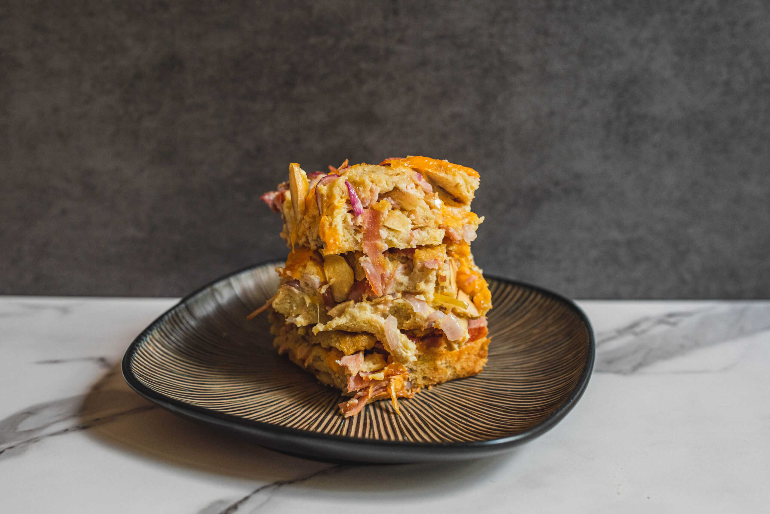 Buttermilk chicken casserole with vegetables and cheese on black plate, ready to serve, comforting baked dish, crispy top, home-cooked meal, hearty comfort food, modern kitchen setting.