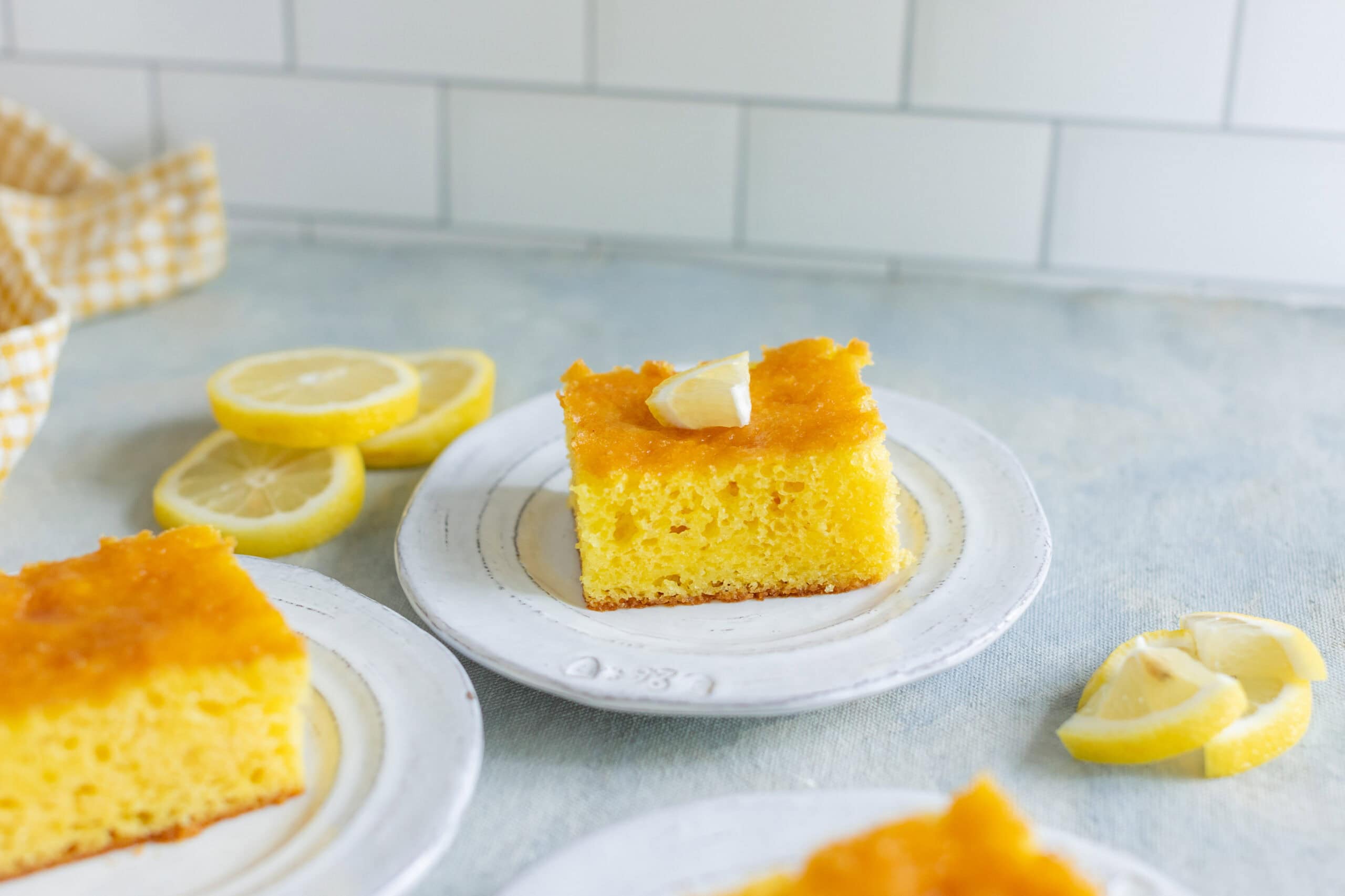 Lemon cake slice with fresh lemon slices and a piece of lemon on top, perfect for lemon desserts and tea time.