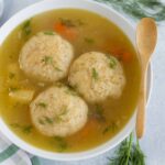 Fluffy matzo ball soup with clear chicken broth and fresh dill, classic comfort food for Passover and Jewish cuisine. Perfectly cooked matzo balls served in a flavorful broth, topped with herbs.
