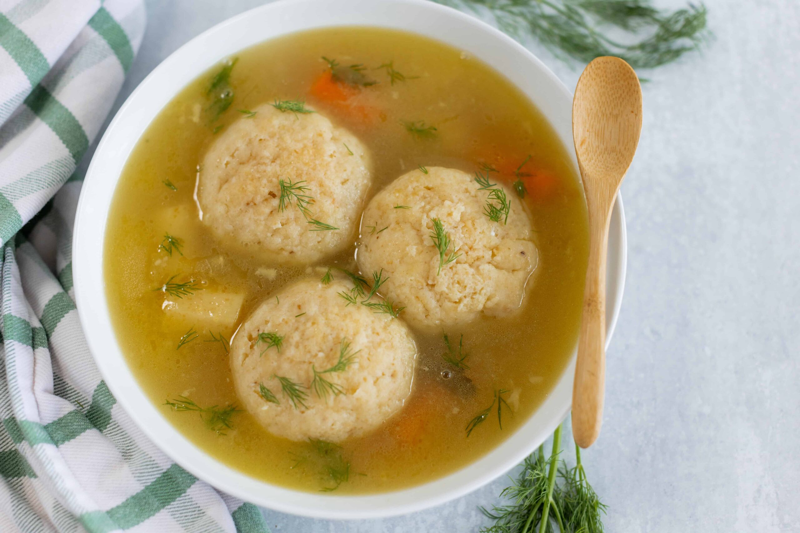 Fluffy matzo ball soup with clear chicken broth and fresh dill, classic comfort food for Passover and Jewish cuisine. Perfectly cooked matzo balls served in a flavorful broth, topped with herbs.