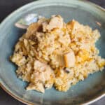 Creamy chicken and egg fried rice served on a stylish green ceramic plate. The rice dish features tender chunks of chicken, scrambled eggs, and seasoned rice, perfect for a comforting meal.