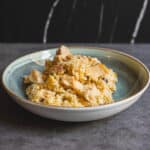 Creamy scrambled eggs with chicken pieces on a ceramic plate, served as a hearty breakfast or brunch dish. Perfect for comfort food lovers and egg recipes enthusiasts.