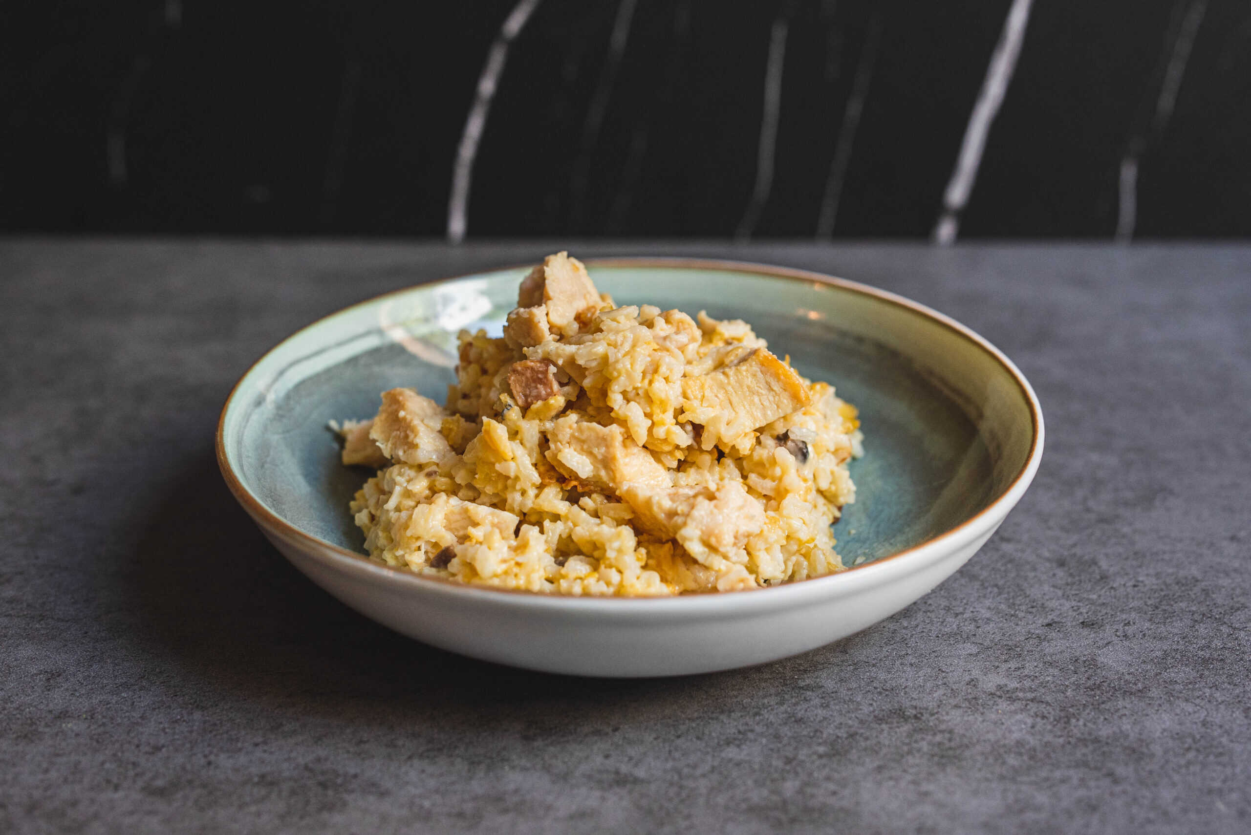 Creamy scrambled eggs with chicken pieces on a ceramic plate, served as a hearty breakfast or brunch dish. Perfect for comfort food lovers and egg recipes enthusiasts.