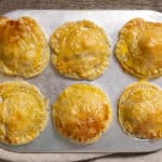 Golden baked chicken pot pies with flakey crusts on a baking sheet, perfect for savory comfort food recipes.
