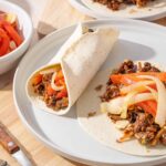 Savory beef taco with sliced onions and peppers on flour tortilla, Mexican street food, authentic homemade taco, delicious filling, restaurant-quality Mexican cuisine.