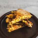 Fluffy breakfast quesadillas filled with scrambled eggs, melted cheese, and bacon served on a black plate. Perfect for a quick, delicious morning meal or brunch.