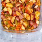 Savory baked potato and sausage hash with colorful vegetables in a glass baking dish. Perfect for hearty breakfast or brunch. Made with potatoes, sausage, bell peppers, and seasonings, ready to serve.