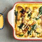 Baked potato casserole with spinach, cheese, and crispy bacon served with creamy cheese sauce on the side. Perfect comfort food recipe for family dinners and gatherings.