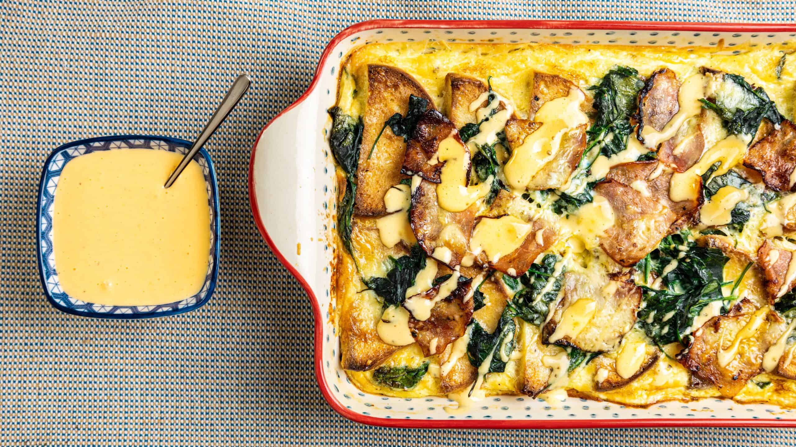 Baked potato casserole with spinach, cheese, and crispy bacon served with creamy cheese sauce on the side. Perfect comfort food recipe for family dinners and gatherings.