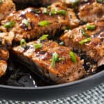 Juicy pan-seared salmon fillets with a glossy glaze, topped with fresh chopped green onions, served in a black skillet for a healthy and delicious seafood dinner.