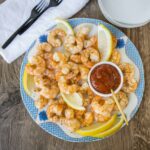 Succulent shrimp cooked with spices served with lemon wedges and spicy dipping sauce on a decorative plate. Perfect for seafood lovers and appetizer recipes.