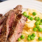 Juicy medium-rare steak with seasoned crust served with fluffy mashed potatoes and fresh green peas. Perfect comfort food meal with tender beef and creamy sides.