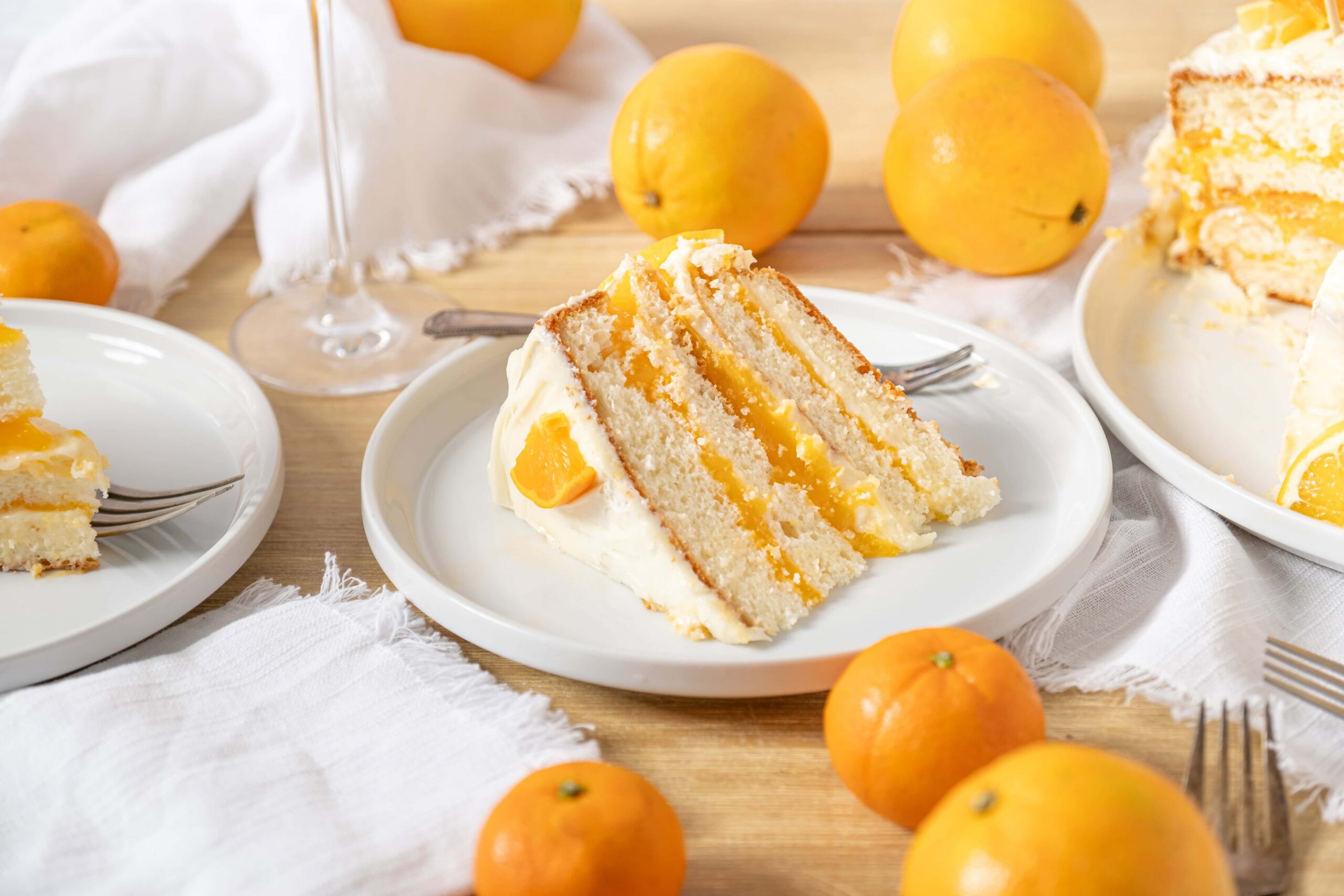 Fresh lemon layer cake with citrus filling and creamy frosting, served on a white plate with whole lemons around, perfect for spring desserts.