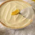 Creamy lemon pie with a golden crust and smooth lemon filling, garnished with fresh lemon wedges, perfect for a delicious dessert or summertime treat.