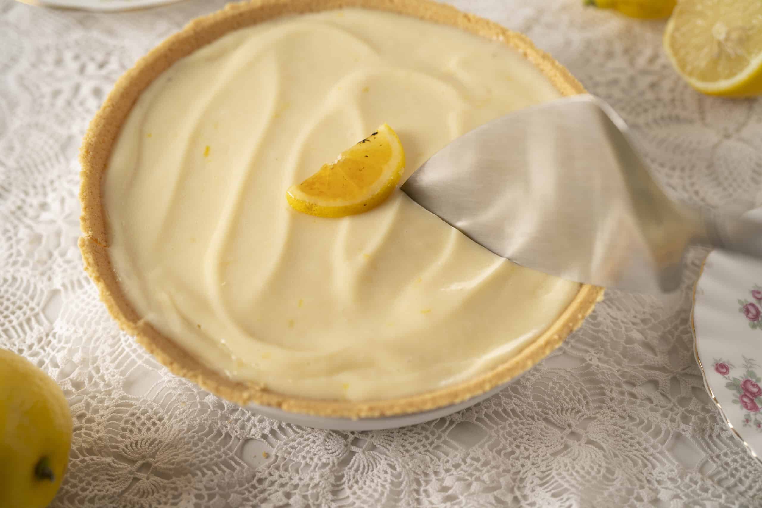Creamy lemon pie with a golden crust and smooth lemon filling, garnished with fresh lemon wedges, perfect for a delicious dessert or summertime treat.