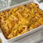 Creamy cheesy pasta casserole with shredded cheese, vegetables, and tender meat in a baking dish, ready to serve as a delicious comfort food meal.