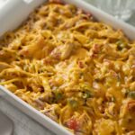 Creamy baked chicken spaghetti casserole with melted cheese and vegetables, served in a white baking dish, ideal for family dinners and comfort food recipes.