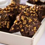 Rich chocolate walnut brownies served in a white baking dish, topped with chopped walnuts, perfect for dessert or coffee breaks, homemade decadent brownies recipe, popular for special occasions.