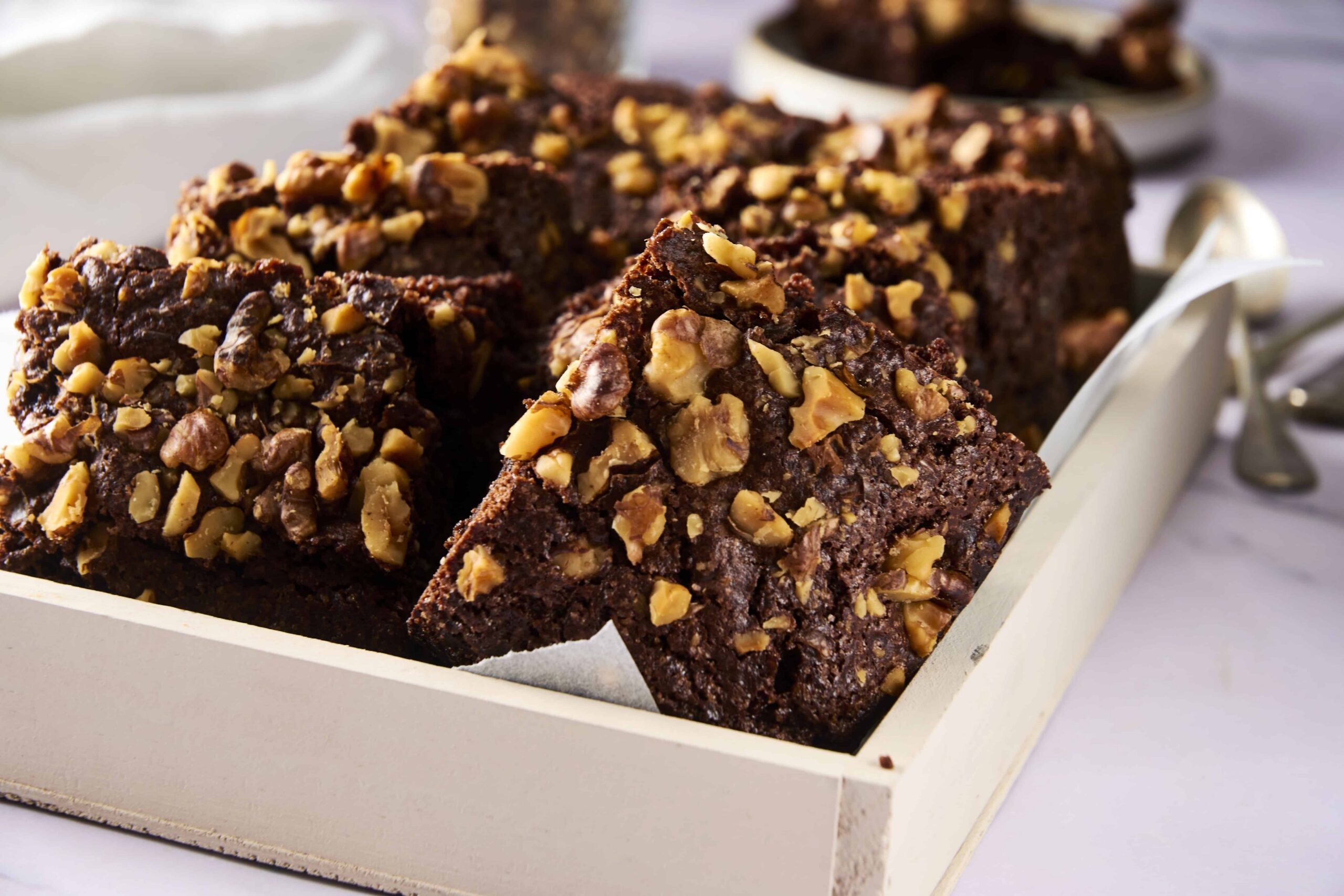 Rich chocolate walnut brownies served in a white baking dish, topped with chopped walnuts, perfect for dessert or coffee breaks, homemade decadent brownies recipe, popular for special occasions.