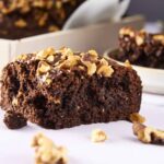 Rich, gooey chocolate brownie topped with chopped walnuts, close-up of a freshly baked chocolate walnut brownie slice, decadent homemade chocolate brownie with walnuts on white baking paper, relevance.