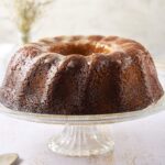 Rich caramel bundt cake with a glazed topping served on a glass cake stand, perfect for dessert or special occasions.