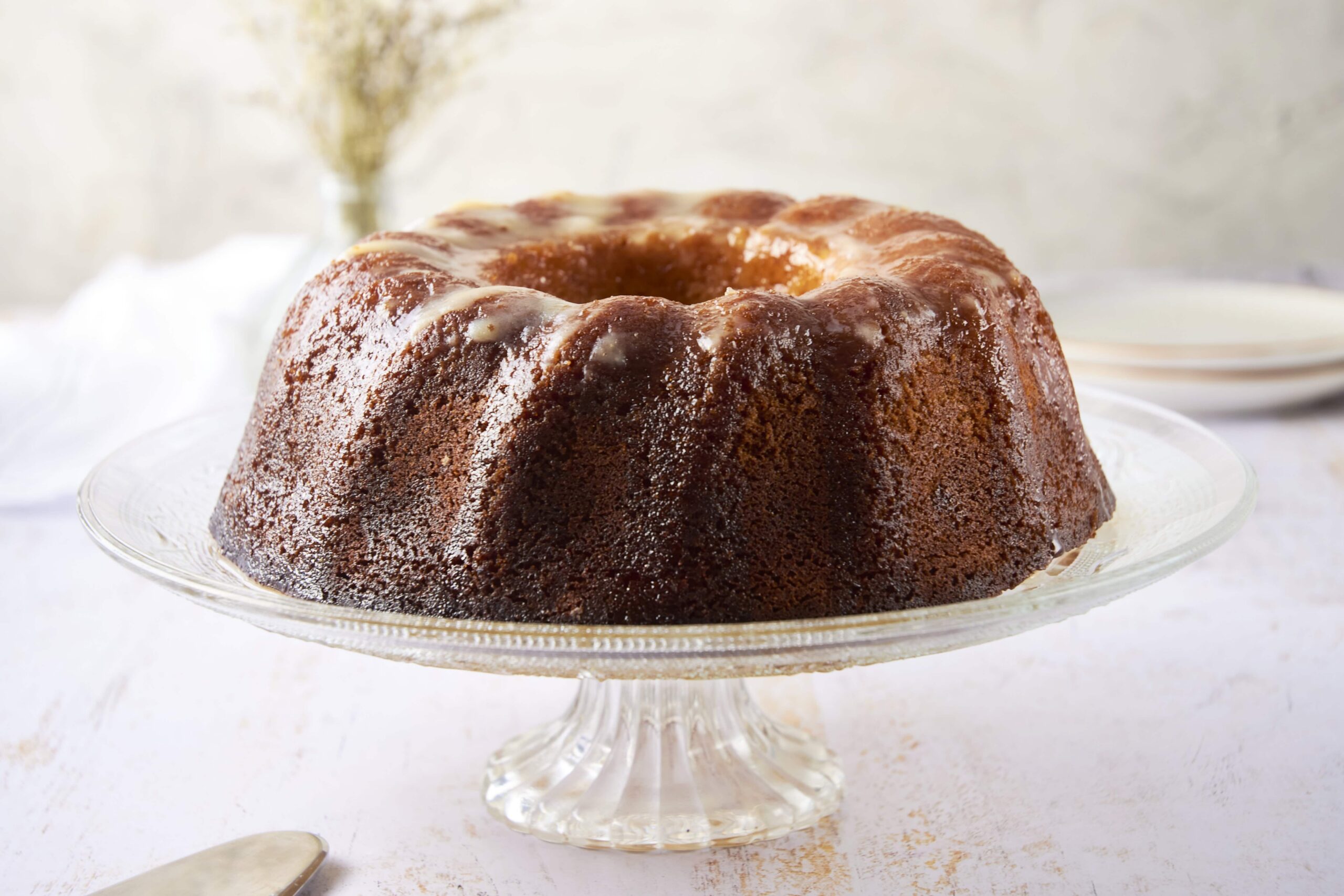 Rich caramel bundt cake with a glazed topping served on a glass cake stand, perfect for dessert or special occasions.