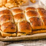 Golden brown dinner rolls topped with poppy seeds, baked to perfection in a parchment-lined tray. Soft, fluffy bread with a slightly crisp crust, ideal for breakfast or dinner.