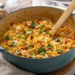 Creamy chicken and vegetable tortilla soup in a turquoise Dutch oven with fresh cilantro and shredded cheese garnishes.