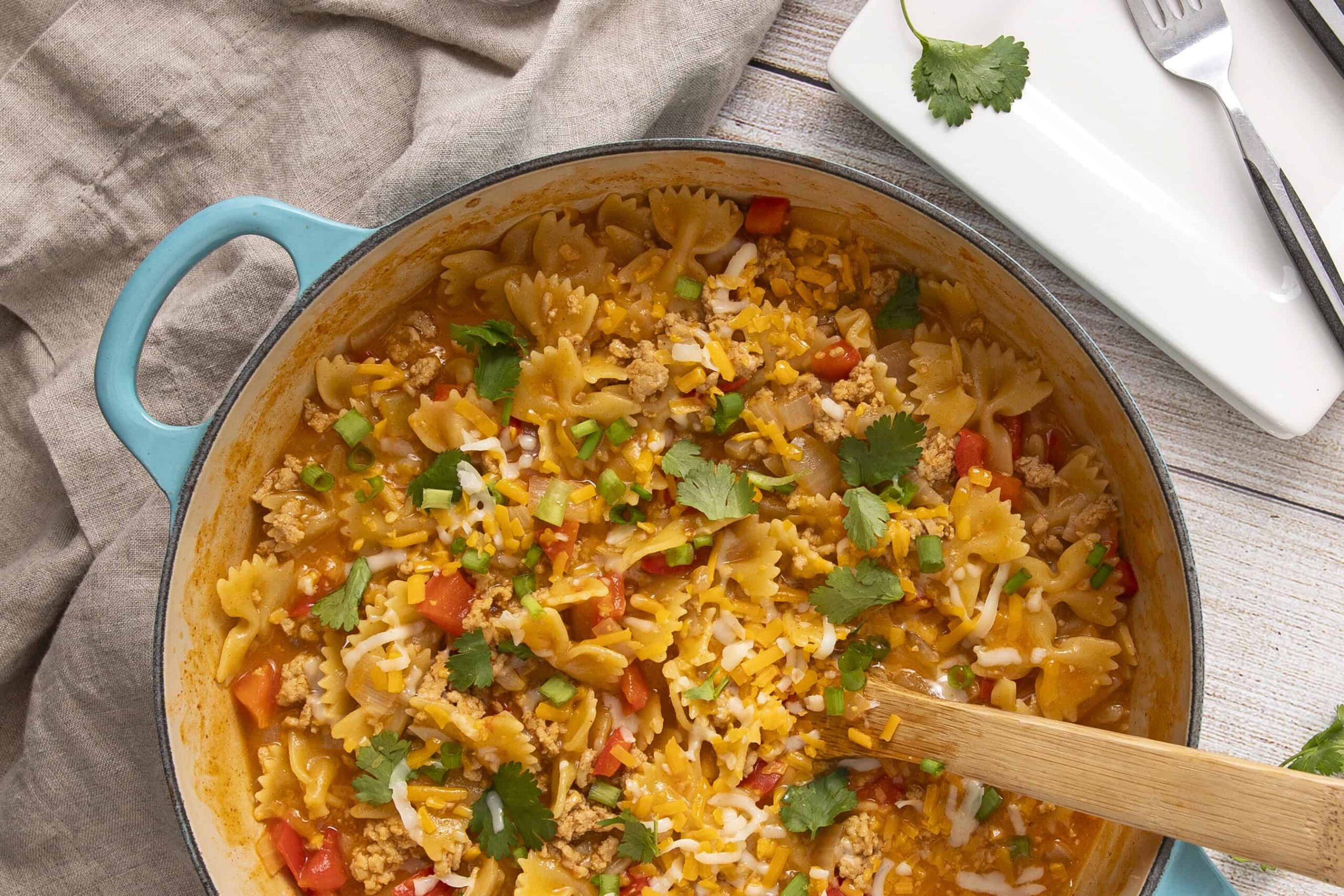 Comforting ground turkey chili with pasta, topped with shredded cheese and fresh cilantro in a rustic skillet. Perfect for cozy dinners and easy weeknight meals.