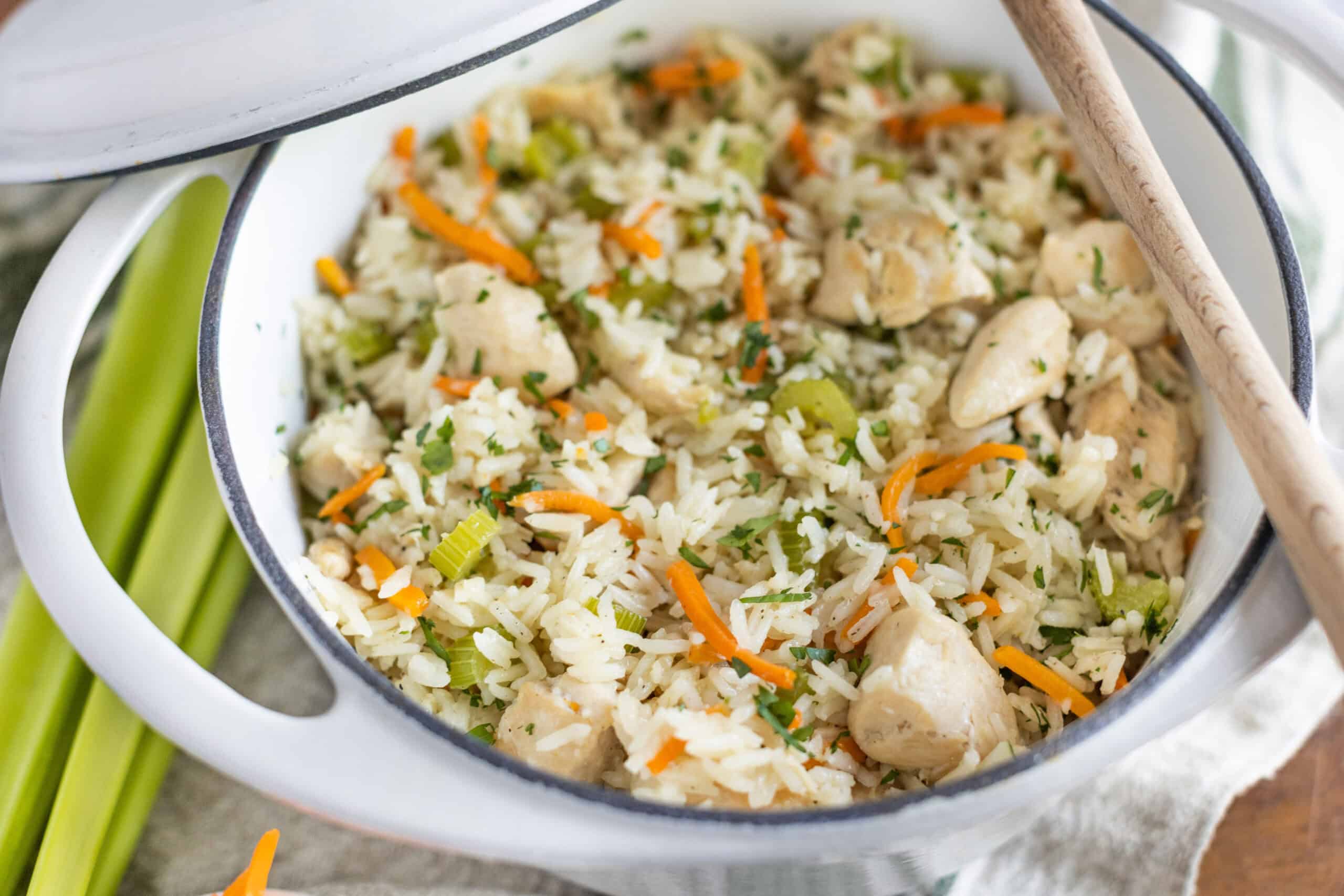 Savory chicken and vegetable fried rice served in a white enamel bowl, garnished with herbs, featuring diced chicken, rice, carrots, and celery, perfect for quick, easy, and delicious homemade meals.