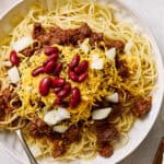 Tender spaghetti with seasoned ground beef, topped with shredded cheese, red bean, and chopped onions, served with fresh lettuce salad on the side. Perfect for a hearty, quick dinner.
