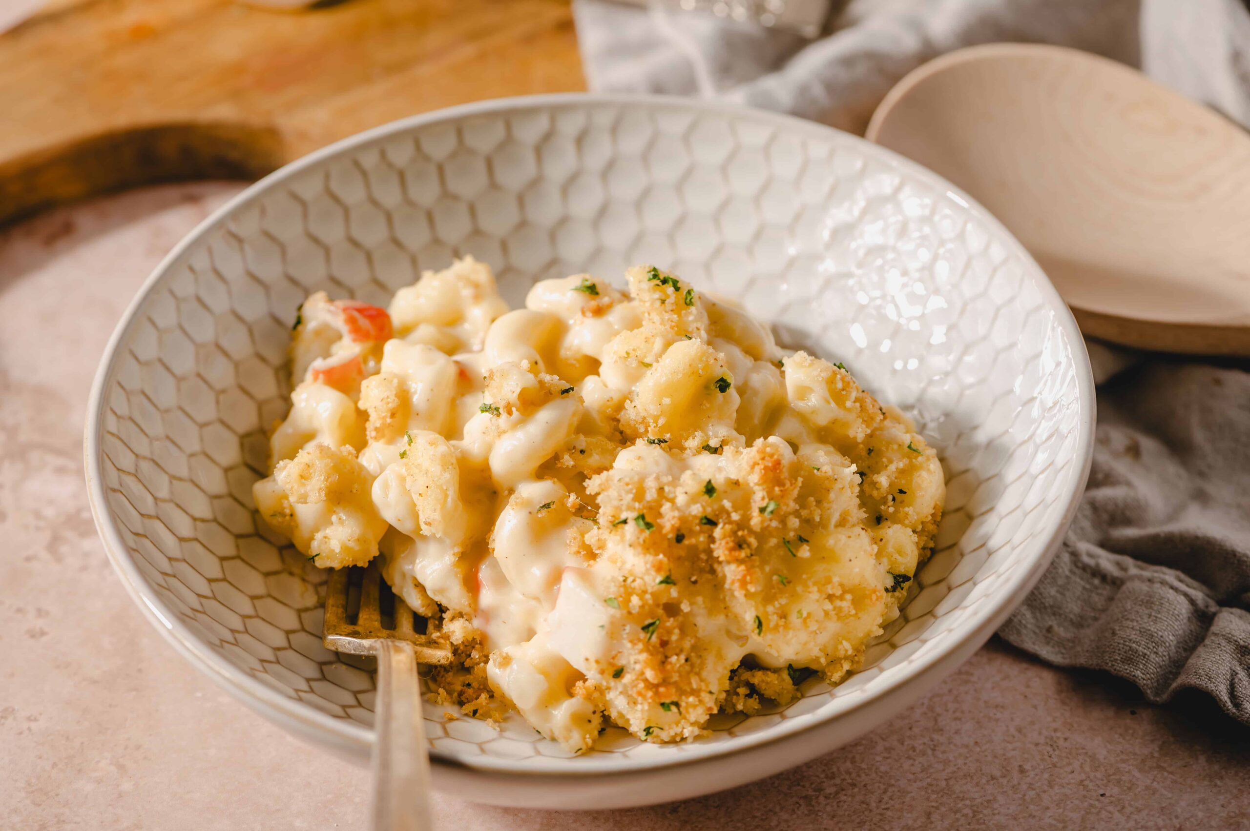 Creamy cauliflower casserole topped with breadcrumbs, garnished with herbs, served in a textured white bowl for a comforting vegetarian dish.