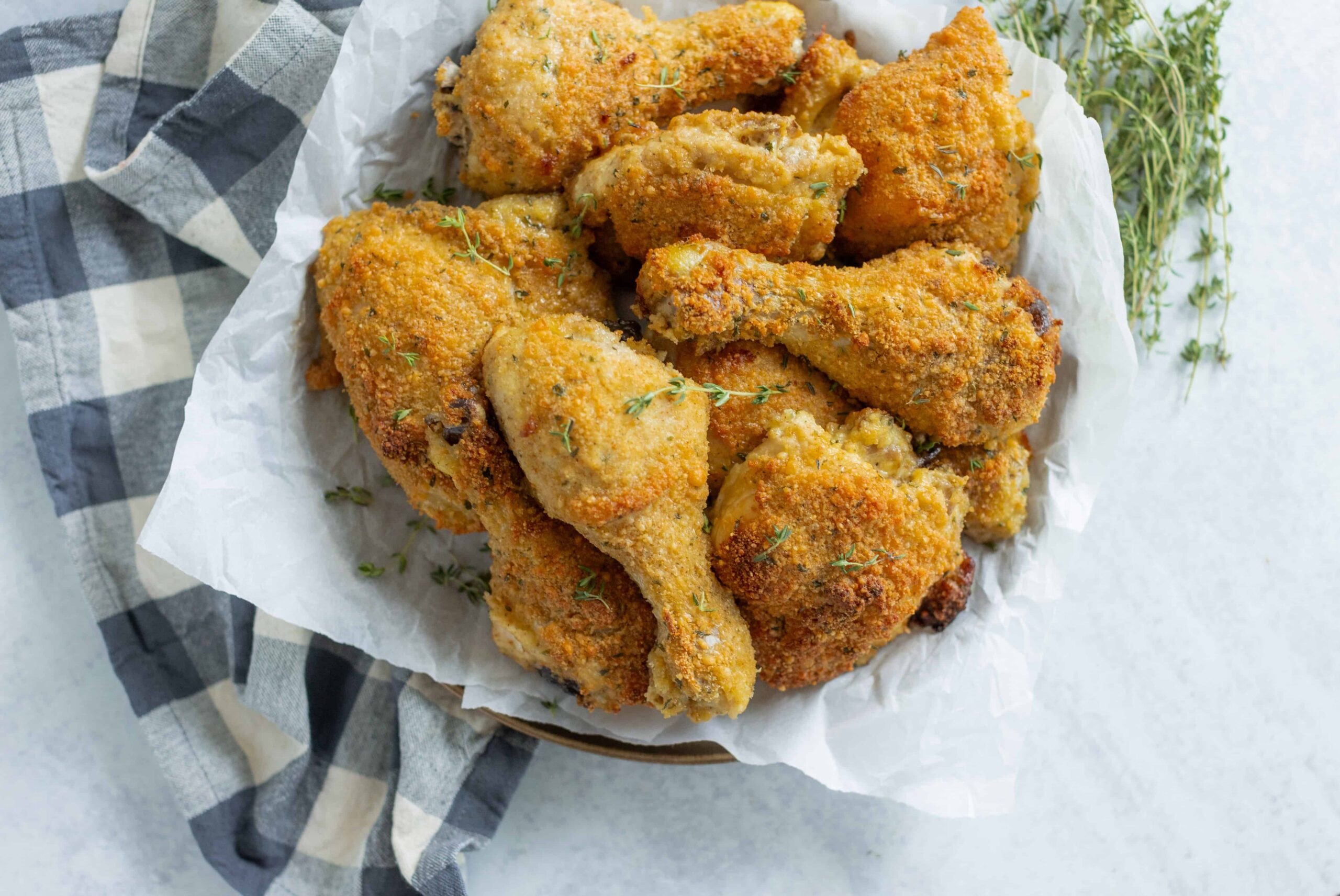 Crispy baked chicken drumsticks on parchment paper with fresh herbs, perfect for crispy fried chicken recipes and comfort food meals.