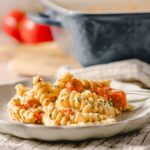 Creamy pasta with cherry tomatoes, garnished with chopped herbs on a white plate for an easy and delicious recipe.