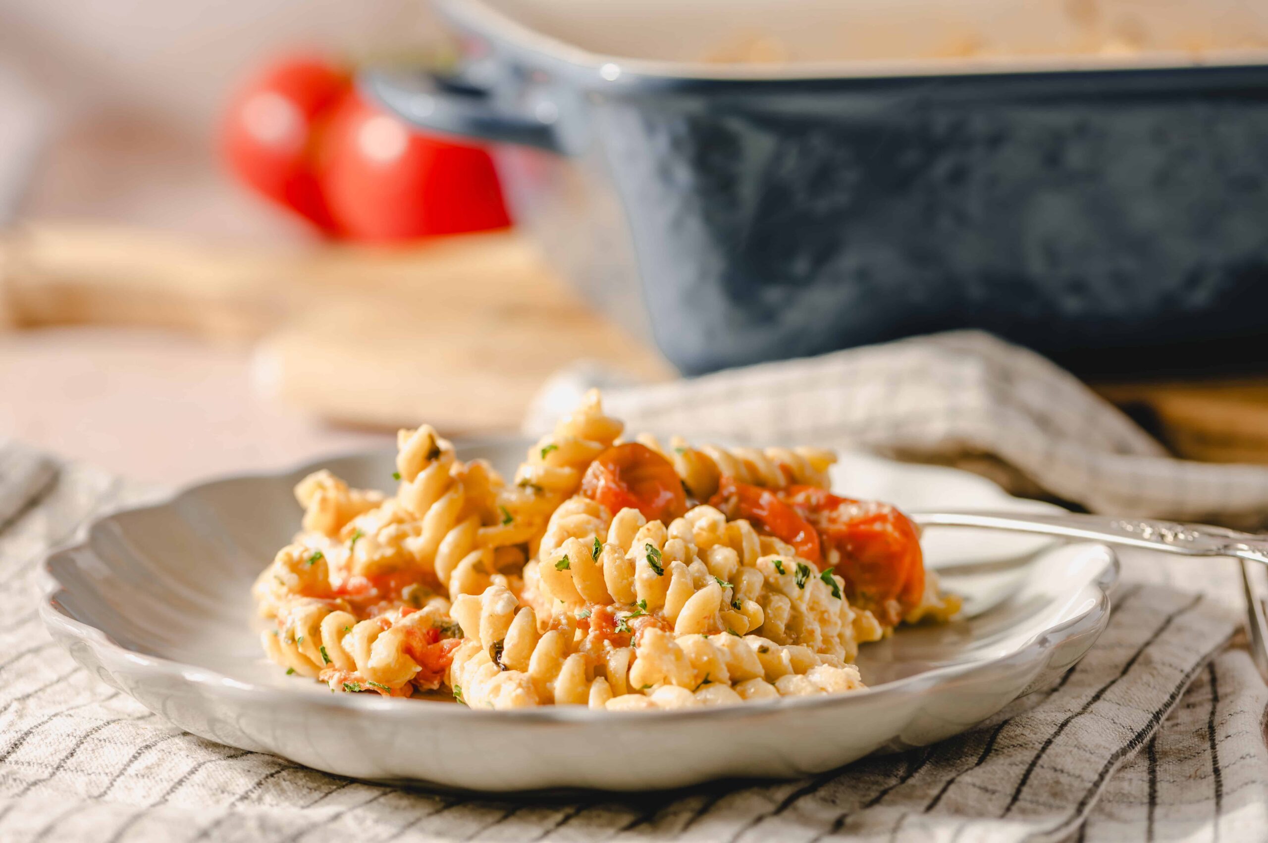 Creamy pasta with cherry tomatoes, garnished with chopped herbs on a white plate for an easy and delicious recipe.