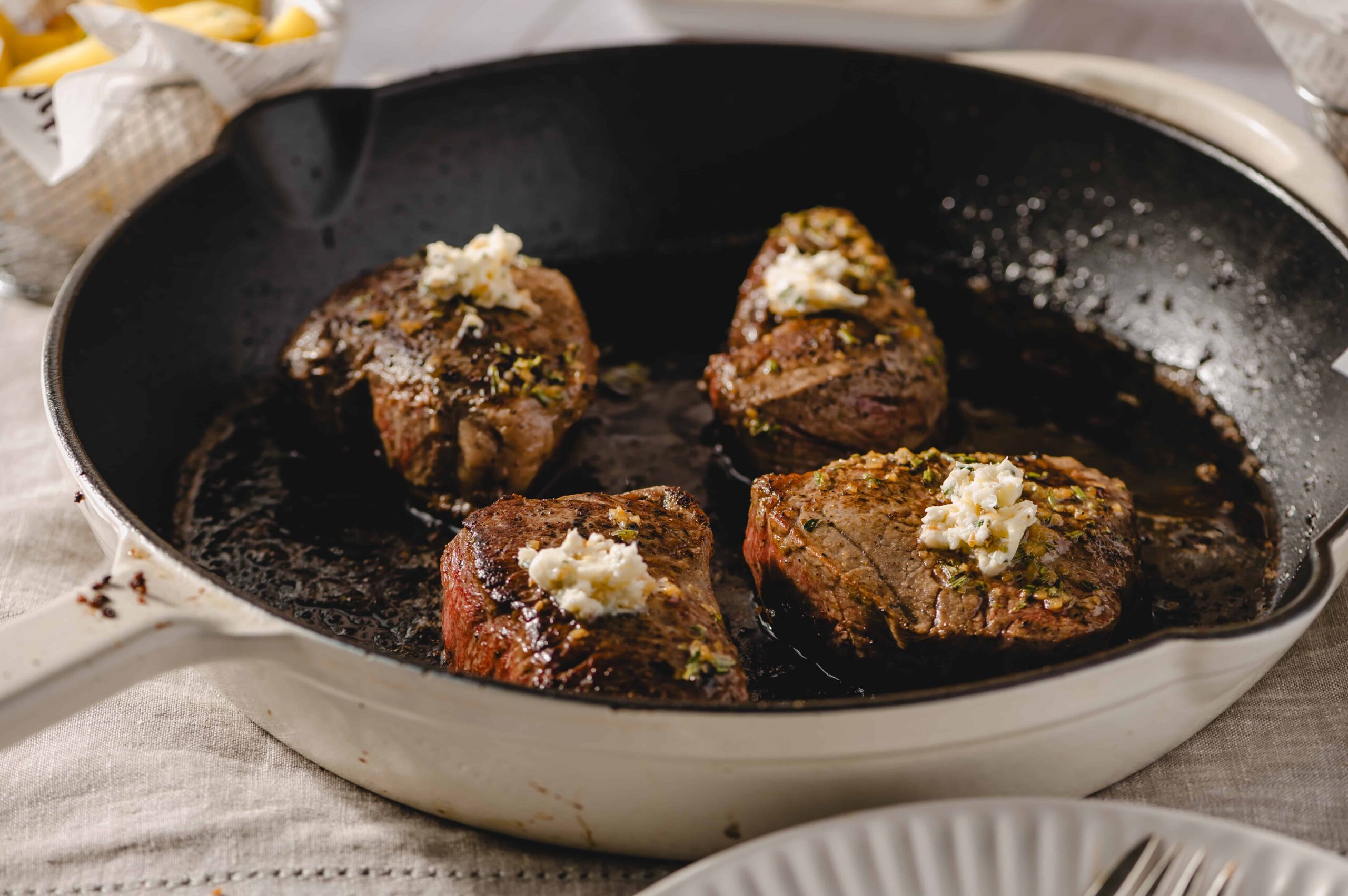 Succulent beef steaks cooked in a cast iron skillet topped with garlic butter and herbs, served for a delicious dinner or special occasion.