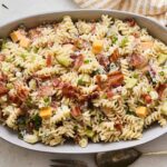 Creamy pasta salad with bacon, cheese, celery, and green onions in an oval serving dish. Fresh, flavorful, and perfect for a quick dinner or potluck.