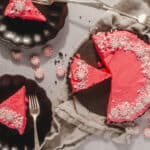 Sweet peppermint chocolate cake with pink icing and peppermint candies on top, presented on black plates for dessert, perfect for holiday celebrations, festive dessert ideas, Hey Recipe.